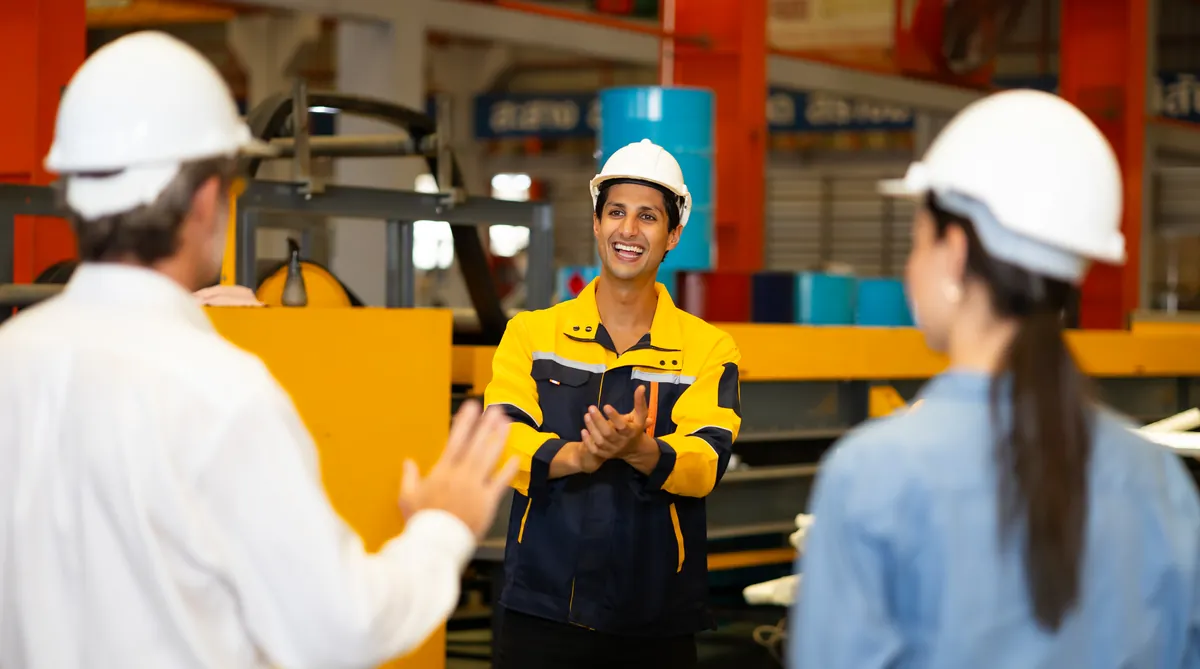 Morning safety briefing with colleagues in hard hats on the factory floor